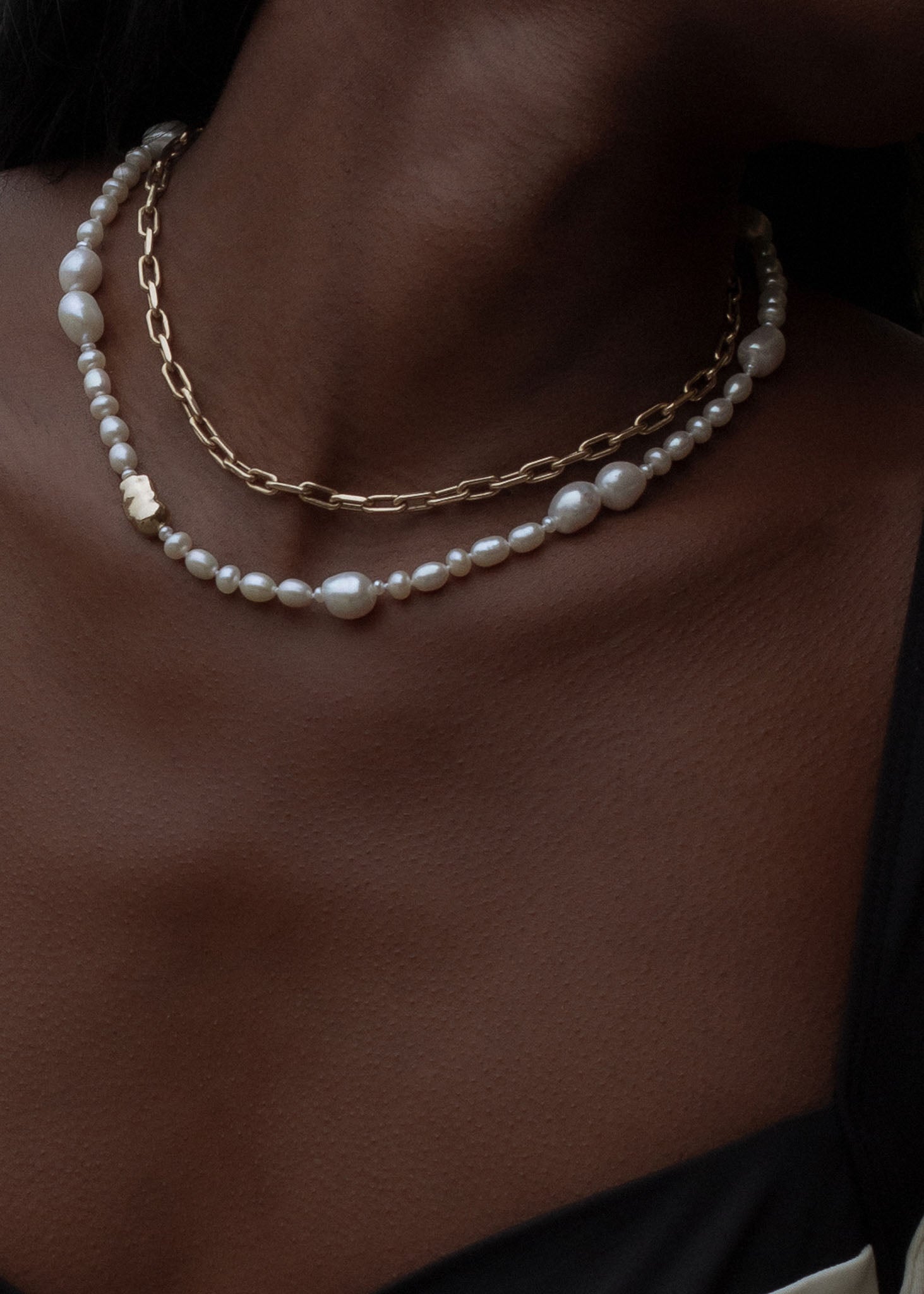 close up of woman wearing a Kinn Studio 14k Gold Lucy Baroque Pearl Necklace layered with a Mia Link Chain Necklace