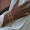 woman in a white top wearing a Kinn Studio 14k Gold Hampshire House Bracelet layered with a Karina Trio Bracelet Diamond, and a Serena Baguette Diamond Bracelet