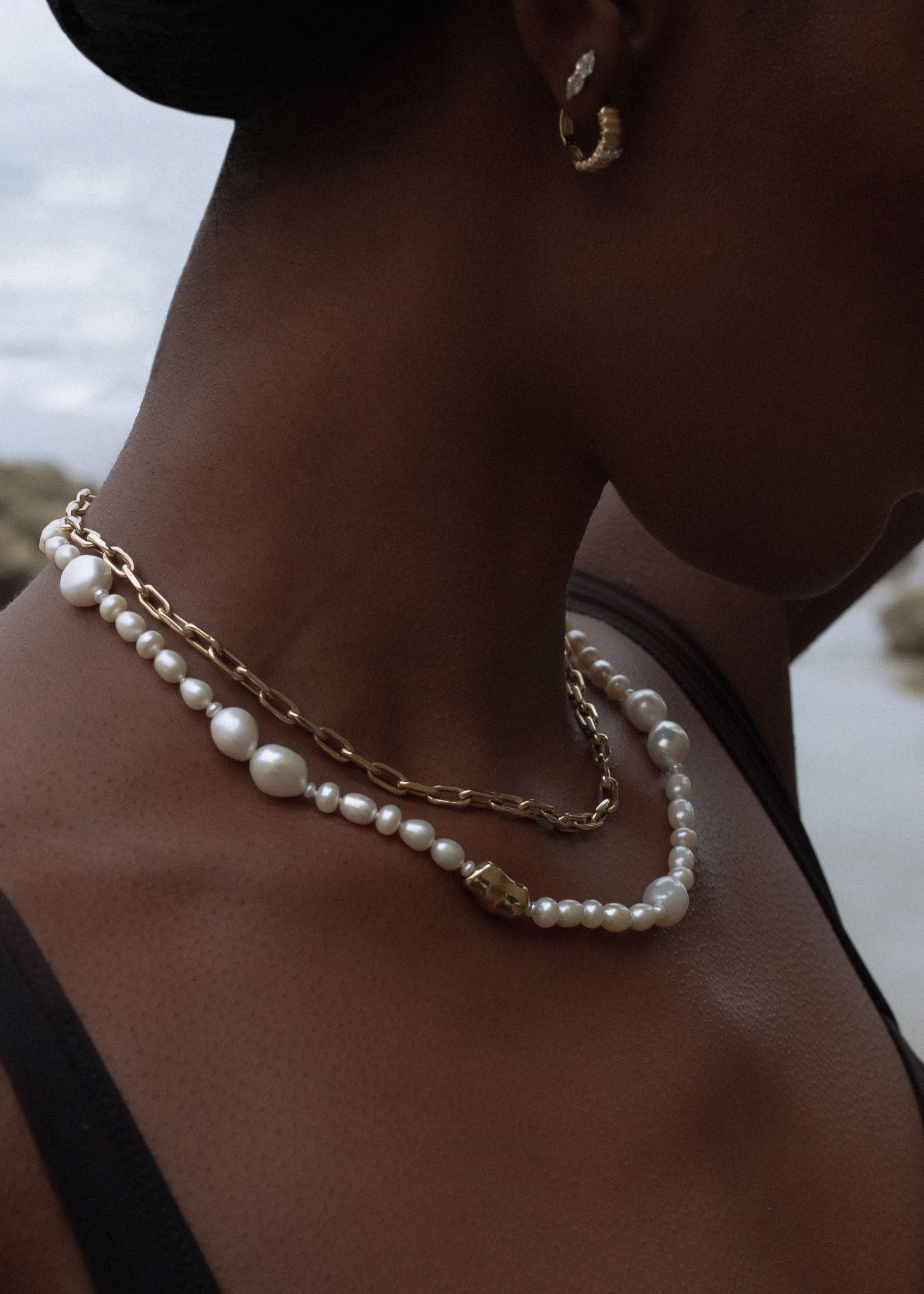 close up of woman wearing a Kinn Studio 14k Gold Lucy Baroque Pearl Necklace layered with a Mia Link Chain Necklace