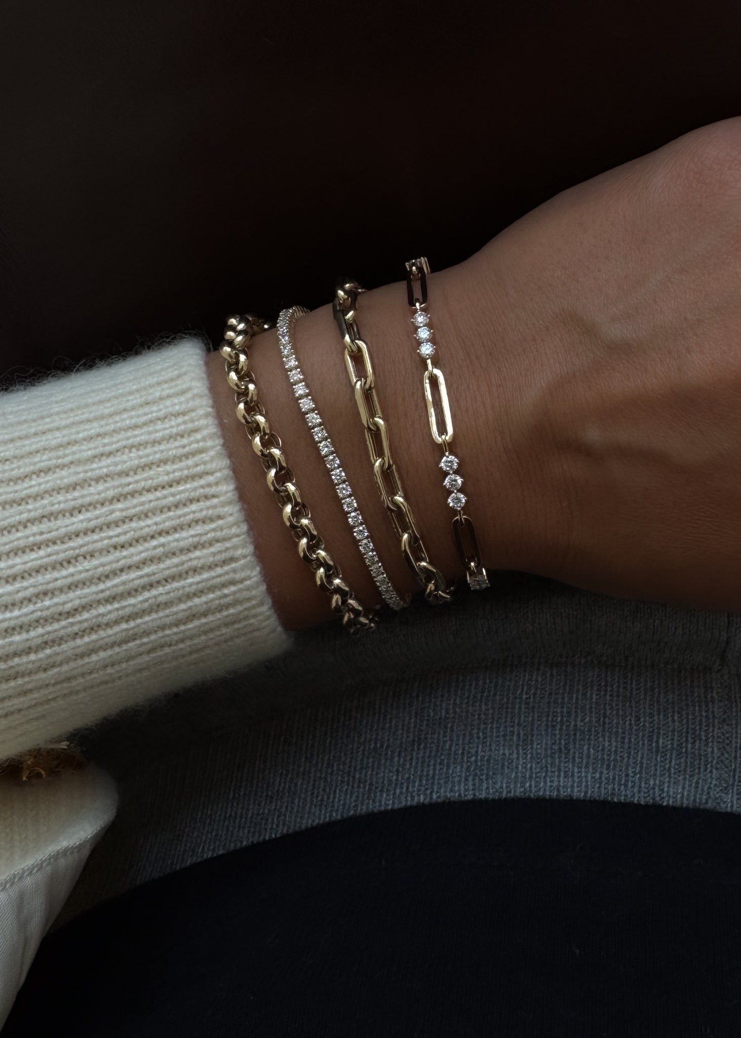 close up of a woman's wrist wearing a Kinn 14k Gold Karina Diamond Trio Bracelet layered with a Mia Link Bracelet, Diana Tennis Bracelet, and a Rolo Chain Bracelet