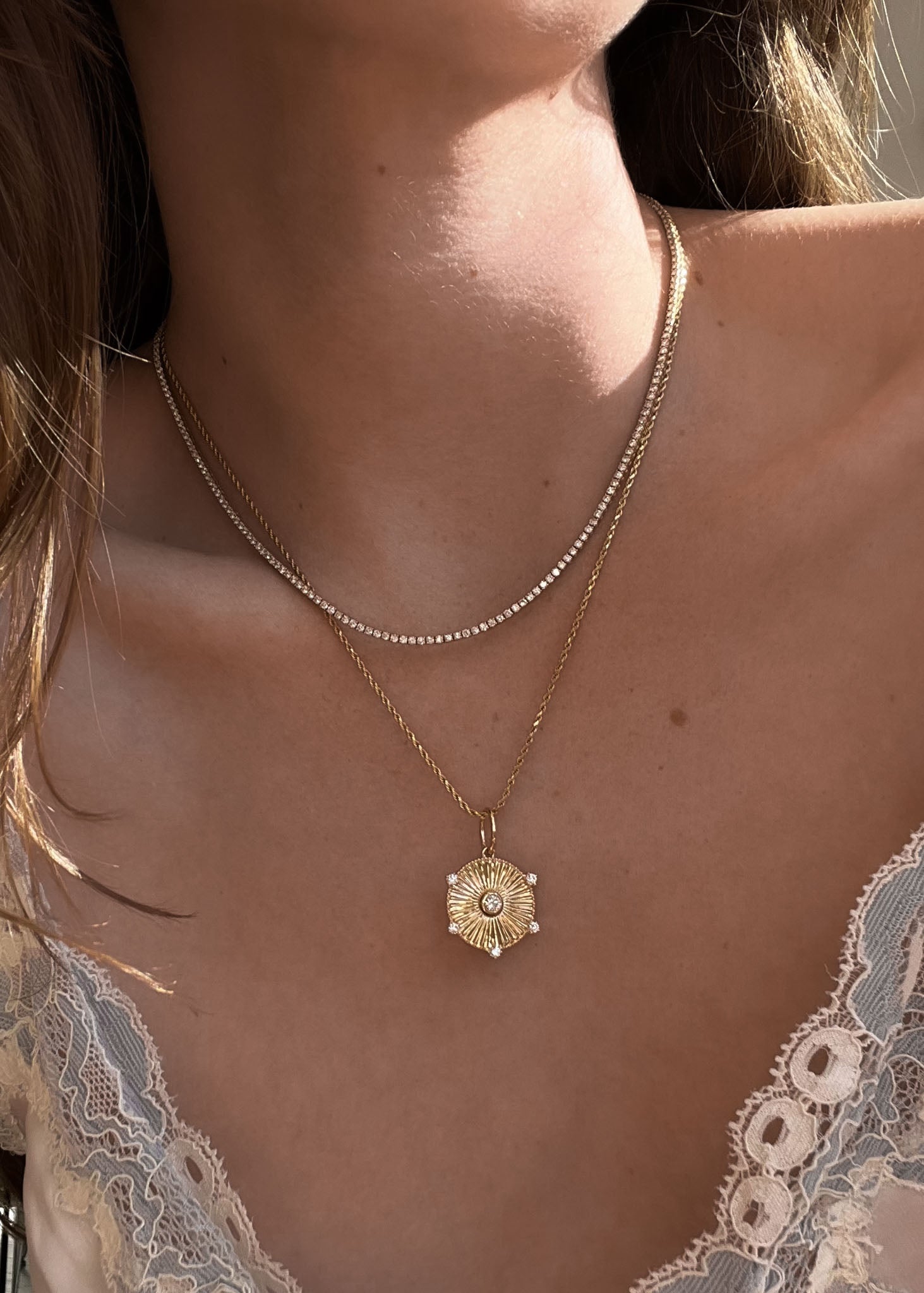 woman in a lace camisole wearing a Kinn 14k Gold Jordyn Ribbed Coin Necklace Diamond on petite rope chain layered with a tennis necklace