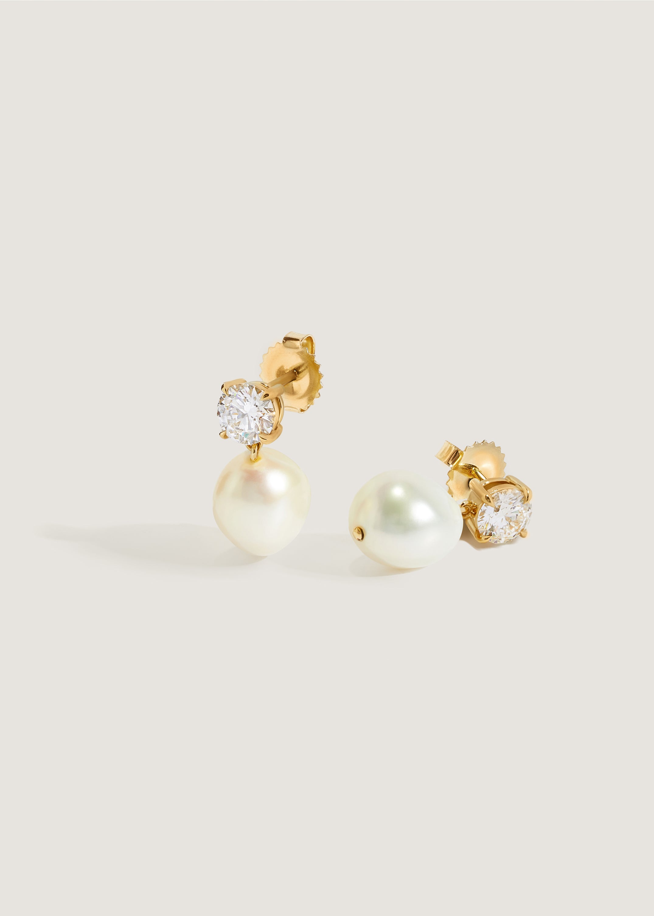 Kinn Studio 14k Gold Delanie Diamond Baroque Pearl Earrings with one laying on its side