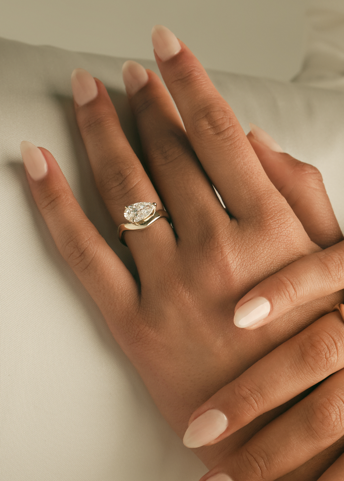 close up of a woman's left hand wearing a Kinn 14k gold Pear Diamond Solei Engagement Ring