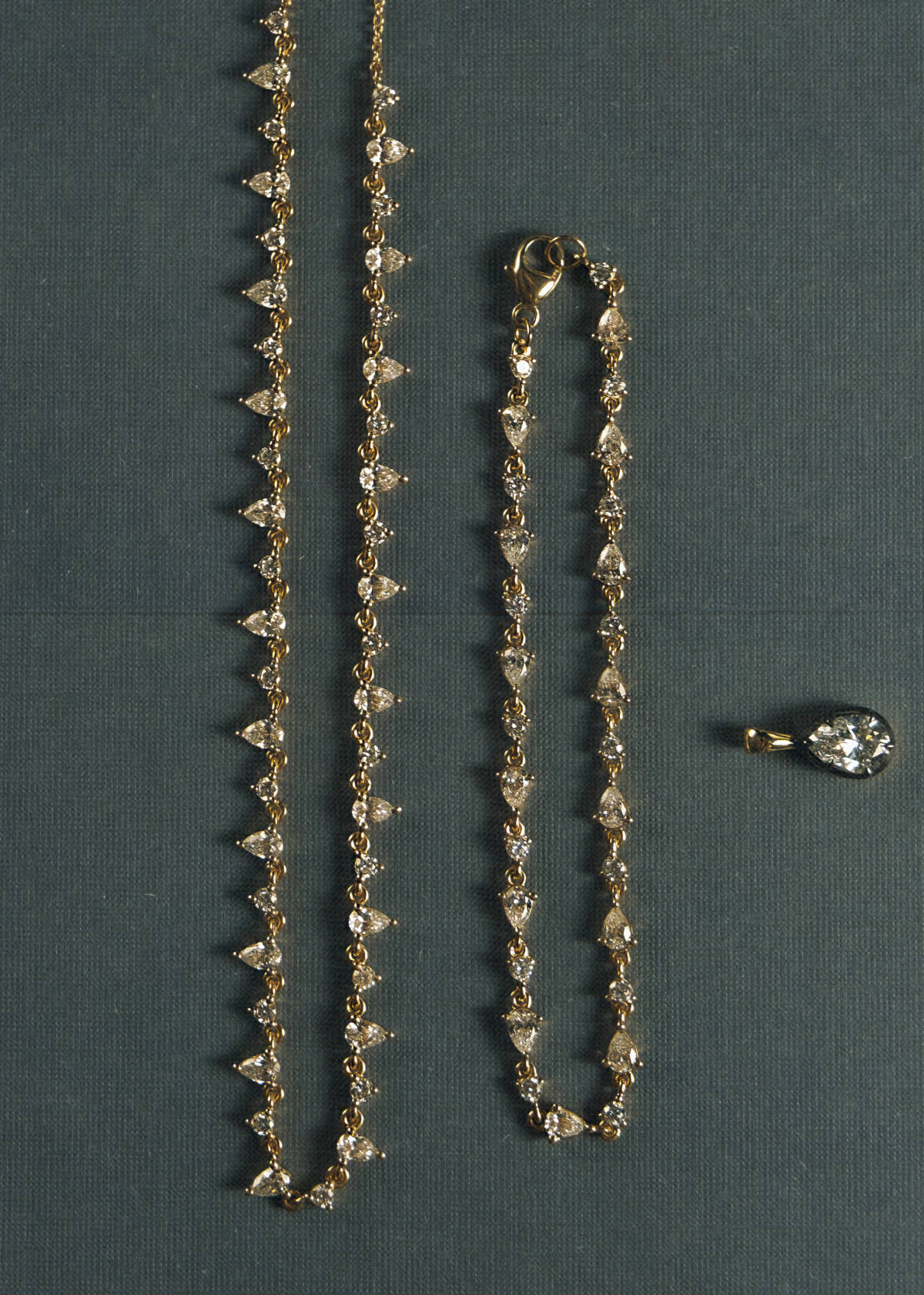 close up of a Kinn 14k Gold Juliette Diamond Row Necklace laying flat next to a Juliette Diamond Row Bracelet and Clara Black Rhodium Pear Pendant