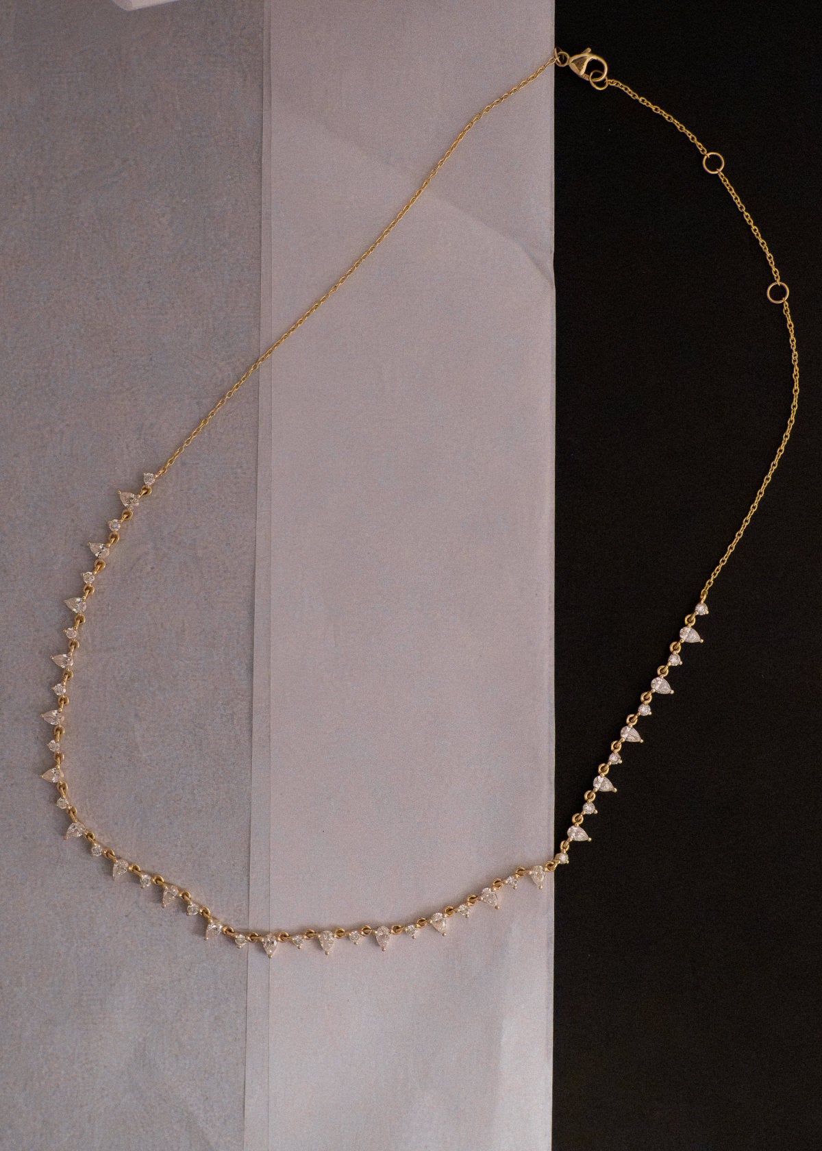 A Kinn 14k Gold Juliette Diamond Row Necklace laying flat against a piece of folded tissue paper