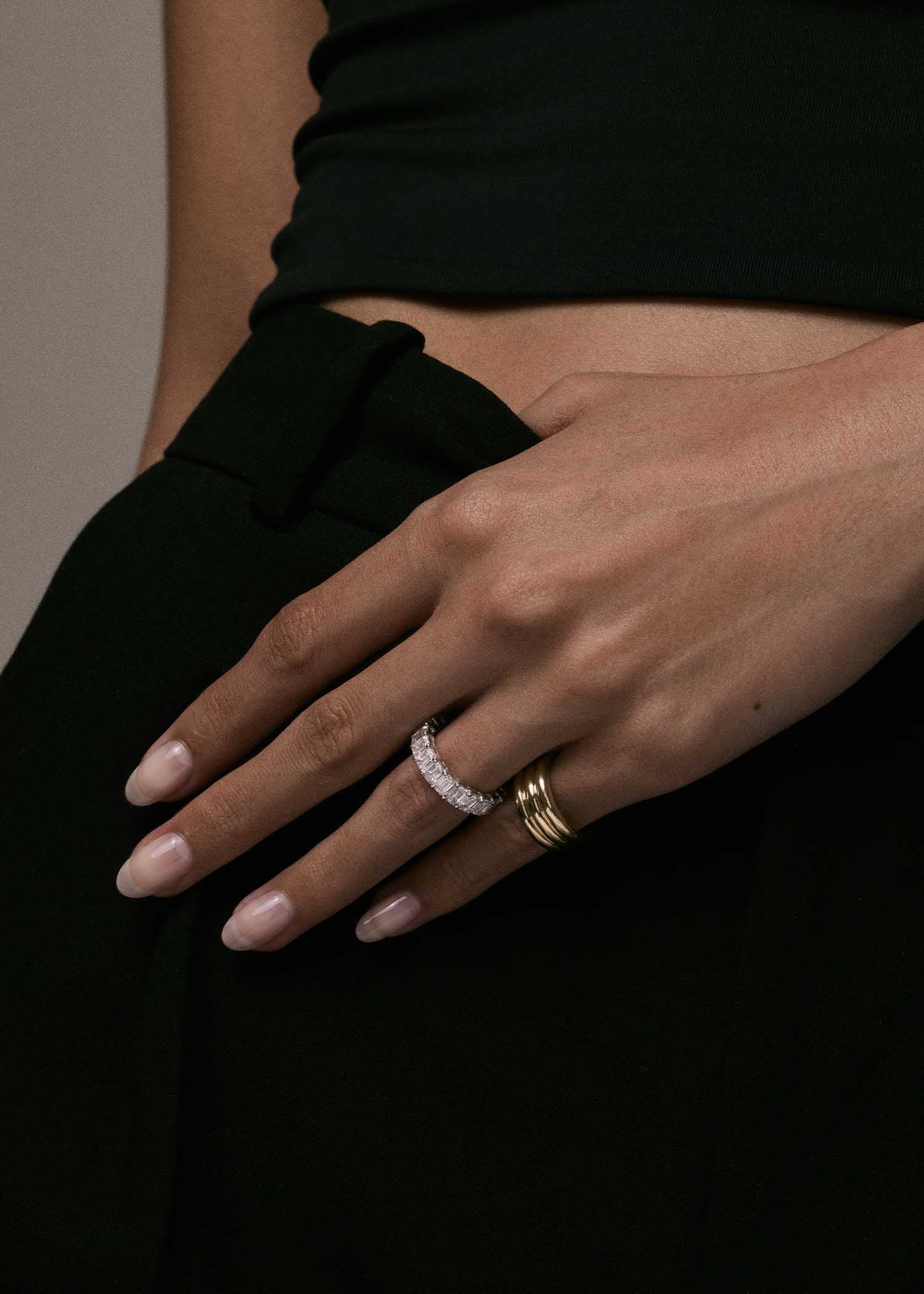close up of woman's hand wearing a Kinn 14k White Gold Blaire Diamond Eternity Band on her ring finger and a Francoise Ellipse Ring on her pinky