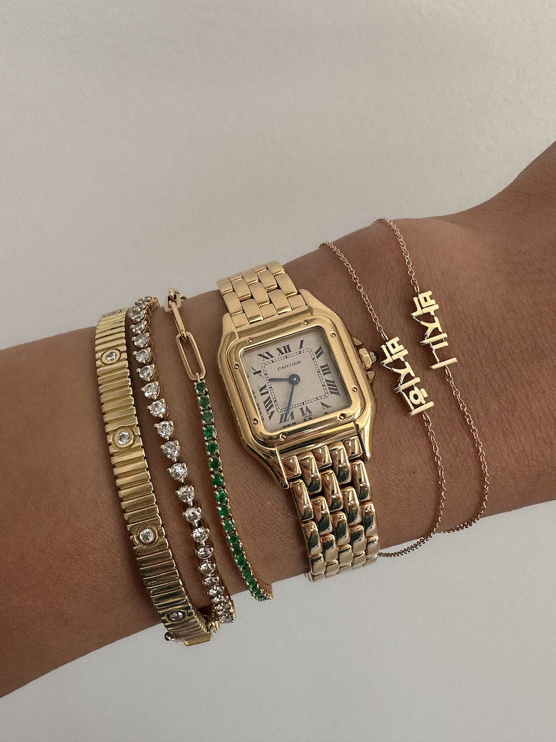 Kinn 14k gold Dear Kaia Korean bracelets stacked with a vintage Cartier watch, Coco Round Emerald Tennis Bracelet, Diana Tennis, and Solis Ribbed Bracelet
