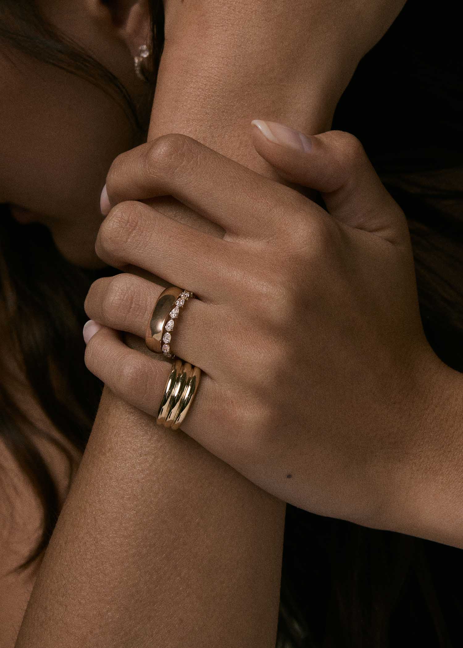 woman wearing a Kinn 14k Gold Françoise Layered Ellipse Ring on her pinky finger with a 5mm Milo Band and Pear Diamond Eternity Band stacked on her ring finger