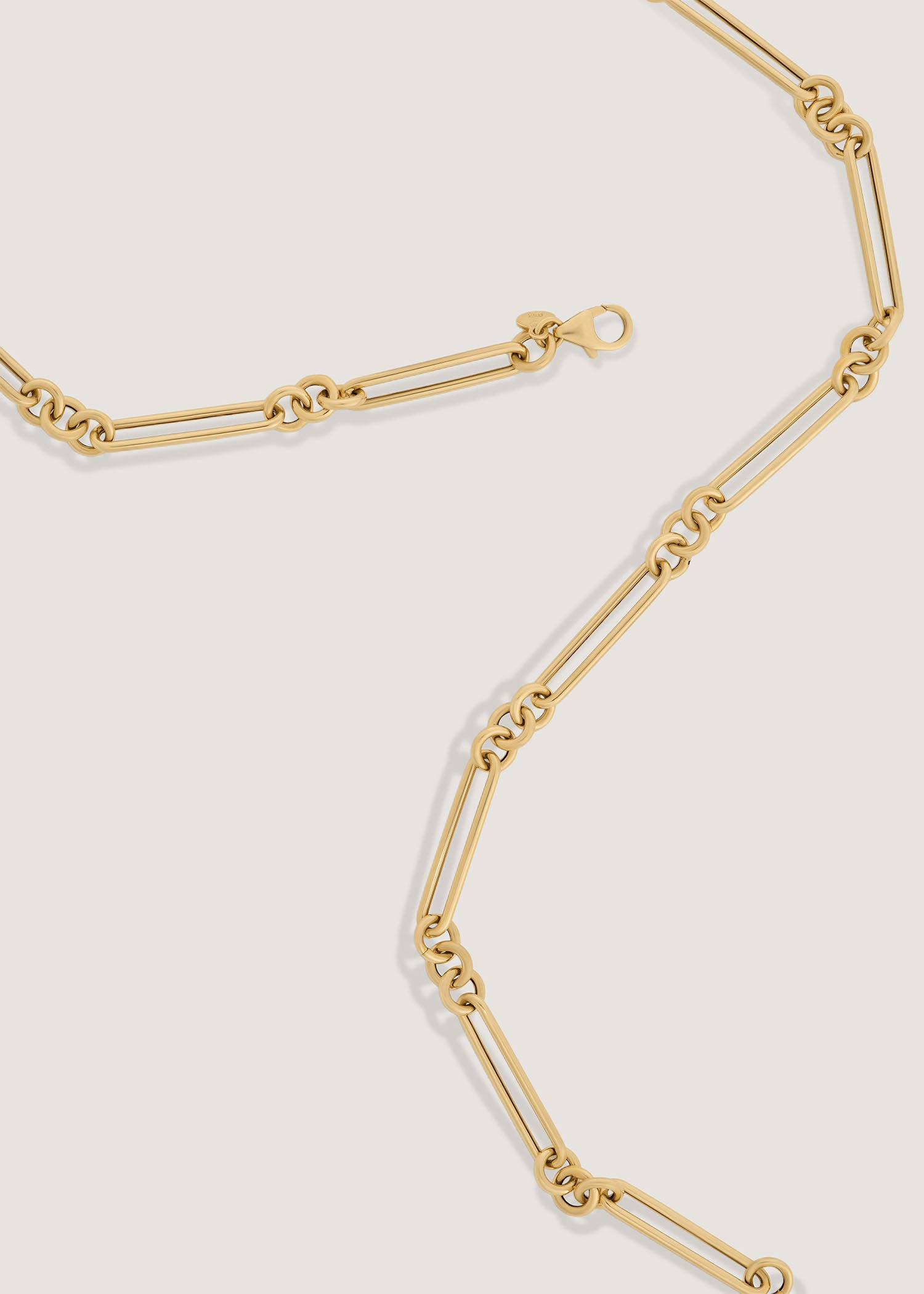 Kinn 14k Gold Mixed Link Chain Necklace laying unclasped and flat against a white background