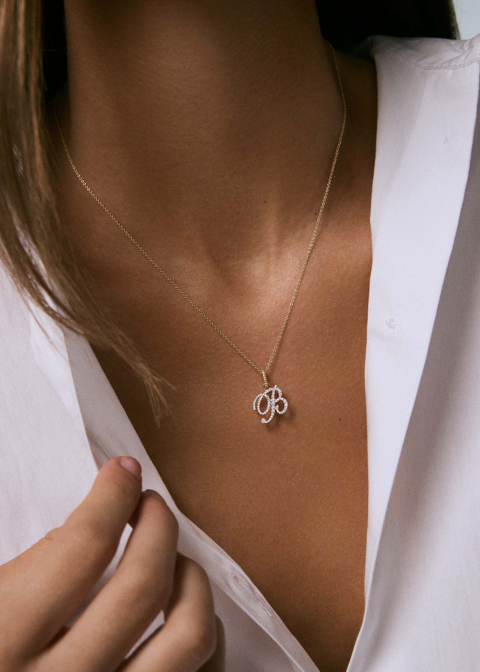 woman in a white shirt wearing a Kinn 14k Gold Pavé Love Letter "B" Diamond Pendant on a chain necklace