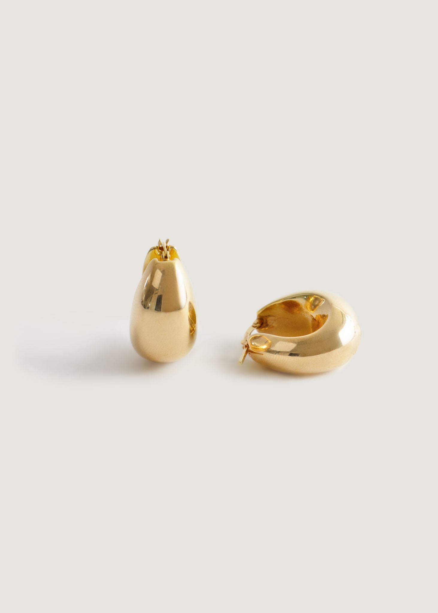 Kinn 14k Gold Bold Teardrop Hoop Earrings with one earring upright and one laying on its side